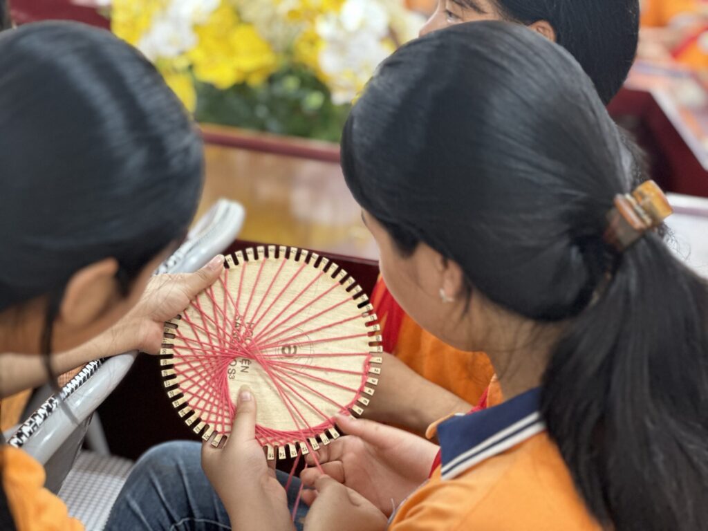 Học sinh tạo hình tim bằng đan dây len Students create a heart shape by weaving yarn